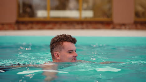 Der-Junge-Kaukasische-Mann-Schwimmt-Im-Außenpool-Des-Modernen-Thermalbadkomplexes-Zum-Entspannen-Und-Erholen